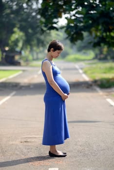 Pregnant mother posing on the outdoor when summer