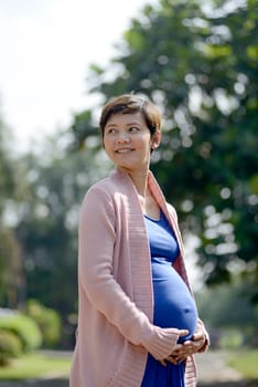Pregnant mother posing on the outdoor when summer