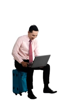 Man sit on the suitcase, working with laptop, isolated over white.