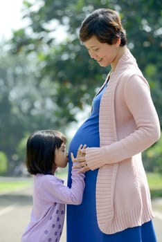 Pregnant mother and her daughter posing on the outdoor when summer