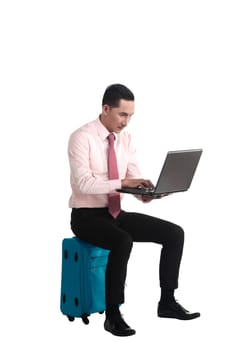 Man sit on the suitcase, working with laptop, isolated over white