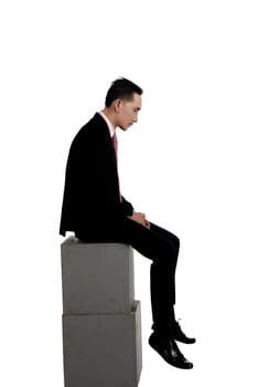 Asian business man feeling sad sitting on the box isolated over white