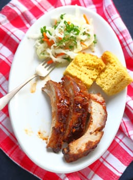 Overhead view of garlic-barbecue sauce-glazed pork baby back ribs with cornbread and coleslaw