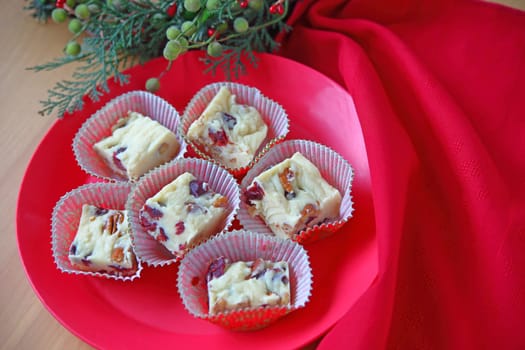 White chocolate candy with dried cranberries and pecans with Christmas greenery and red napkin