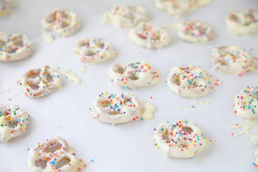 White chocolate-covered miniature pretzels with colorful sprinkles