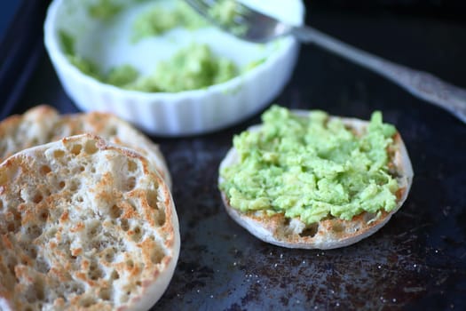 English muffins with avocado toast on old metal surface