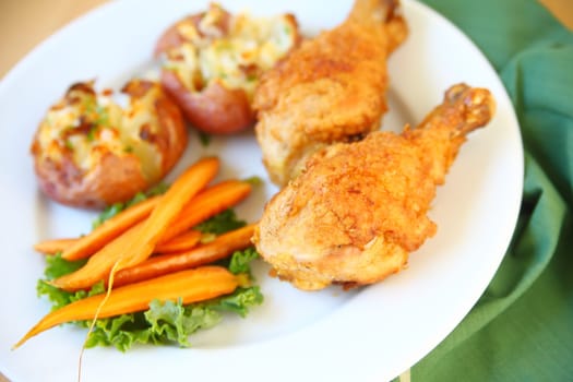 Two fried chicken legs with smashed potatoes and carrots