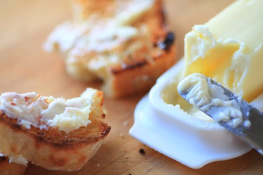 Broken slice of buttered toast with knife and butter dish