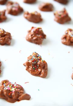 Chocolate candies with nuts and multicolored sprinkles on parchment paper