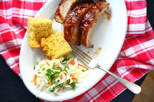 Meal of baby back ribs with garlic barbecue sauce, cornbread and coleslaw