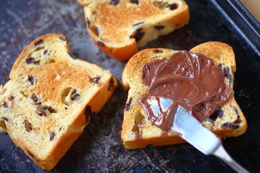 Chocolate chip brioche slices, one with chocolate hazelnut spread on an old cookie sheet pan