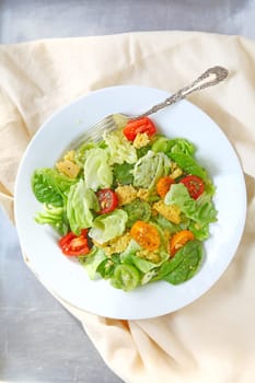 Salad of lettuce, baby spinach and cherry tomatoes with crumbled cornbread