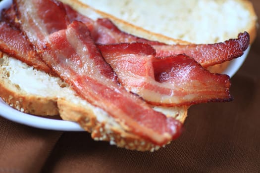 Using thick-sliced bacon to make a sandwich on whole-grain bread with mayonnaise