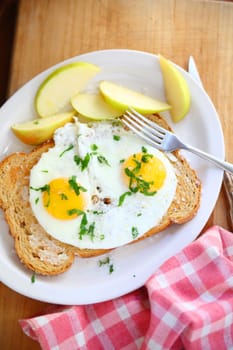 Vertical view of fried eggs over buttered toast and fresh apple slices