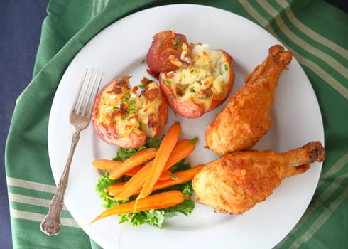 Fried chicken drumsticks with crushed potatoes and roasted carrots