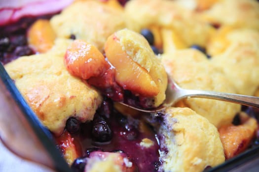 A serving spoon of fresh fruit cobbler with cinnamon