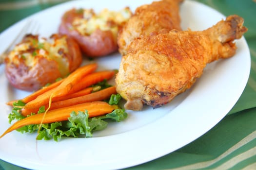 Fried chicken, roasted carrots and crushed potatoes on a white plate with napkin