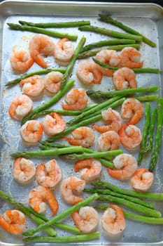 Large shrimp on a sheet pan with asparagus, black pepper and coarse salt