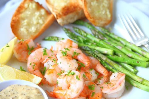 Plate of roasted shrimp and asparagus with garlic bread, lemon and mustard sauce