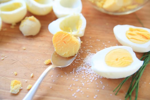 Removing yolks from boiled eggs cut in half