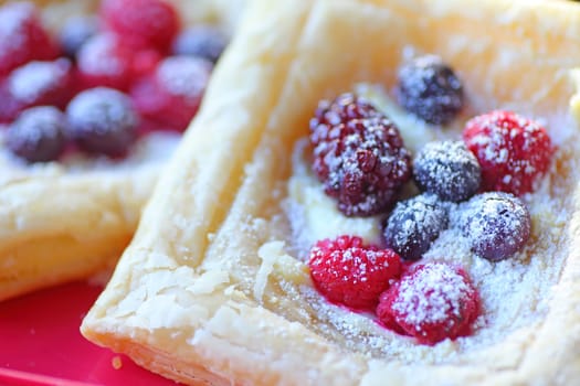Fresh raspberries, blueberries and blackberries on puff pastry with powdered sugar