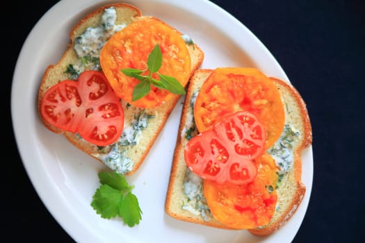 Tomato sandwich with heirloom tomatoes with cilantro mayonnaise on a white platter