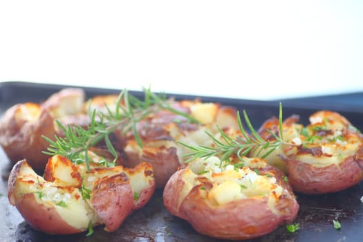 Smashed, roasted potatoes with rosemary and coarse salt on metal pan with copy space