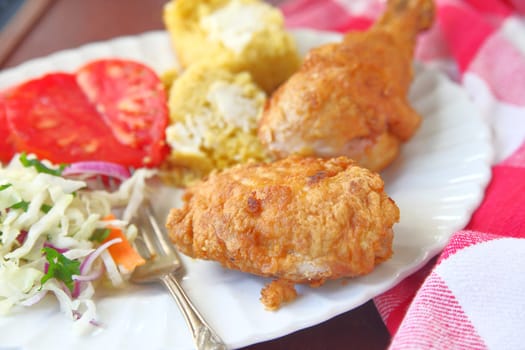 Platter of fried chicken with tomatoes, cornbread and coleslaw