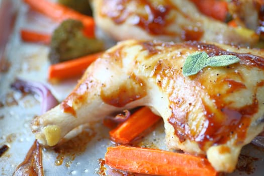 Roast chicken with fresh sage leaves, carrots, broccoli and onions on a sheet pan