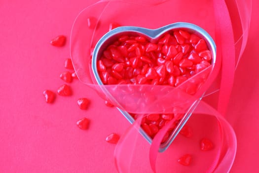 Small heart container filled with tiny red candies with red ribbons and room for text