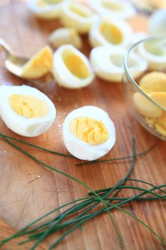 Making deviled eggs with chives on cutting board