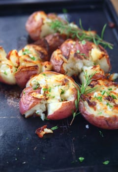 Closeup of crushed potatoes with rosemary on an old metal pan
