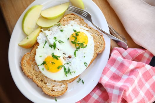 Overhead view of fried eggs on toast with coarse salt and apple slices