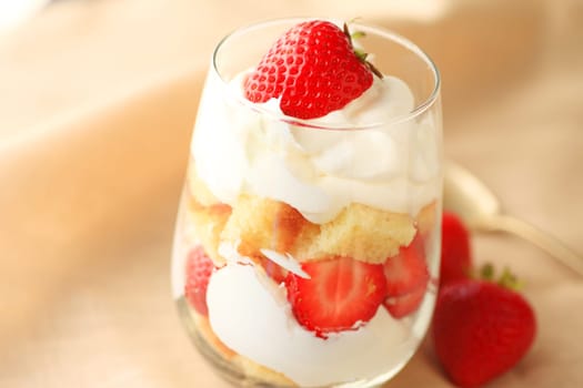 Miniature strawberry trifle in a drinking glass with whipped cream and pound cake cubes