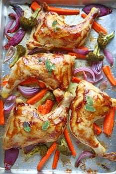 Chicken glazed with hoisin sauce roasting with onions, carrots and broccoli