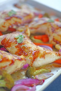 Shallow pan with roast chicken pieces, carrots, onions and broccoli