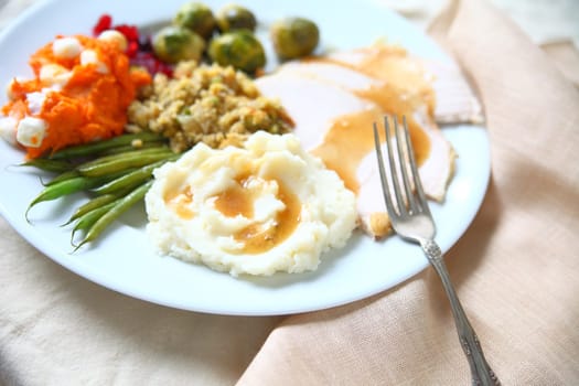 Turkey dinner with stuffing, gravy, mashed potatoes, green beans, sweet potatoes and brussels sprouts with napkin