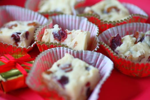 Closeup of Christmas candy with dried cranberries and pecans in holiday paper cups with tiny gift