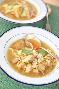 Two bowls of soup with turkey, noodles and fresh sage leaves