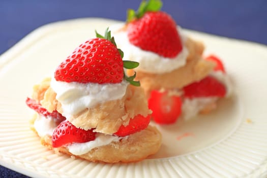 Miniature strawberry shortcakes with whipped cream and fresh berries on a white dish