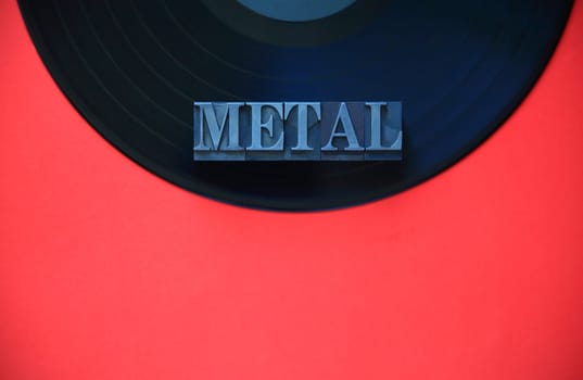 Black vinyl record with the word metal on a red background with copy space