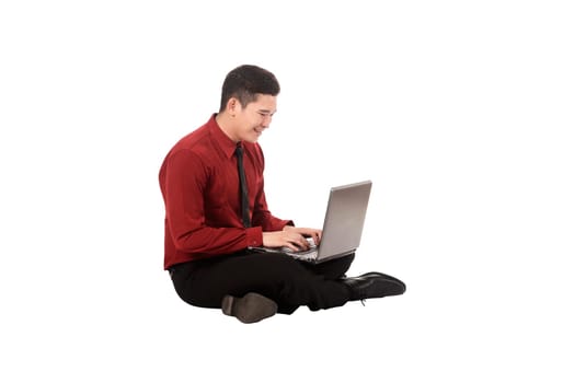 Asian business man working on a laptop and sitting on the floor isolated over white background