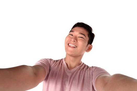Handsome young man holding camera and making selfie isolated over white background