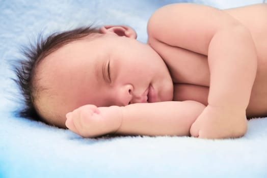 Peaceful baby lying on a bed while sleeping in a bright room over white sheet