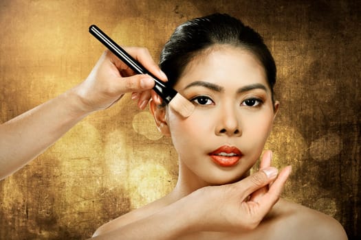 Beautiful asian woman doing makeup over blur background