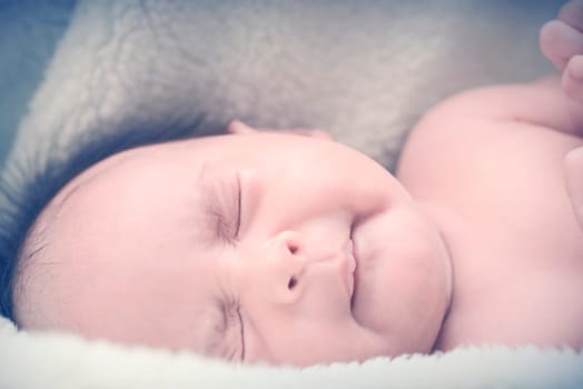 Peaceful baby lying on a bed while sleeping in a bright room over white sheet