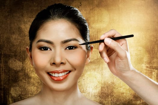 Beautiful asian woman doing makeup over blur background