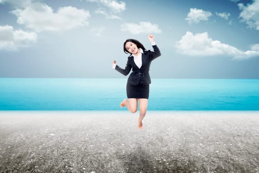 Asian woman jumping on the beach wearing business suit. Business travel concept