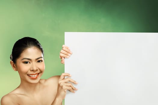 Pretty asian woman holding blank banner over blur background