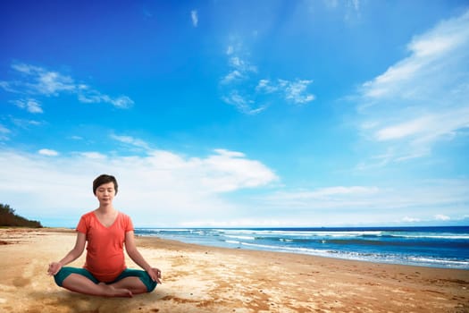 Asian pregnant mother doing yoga on the beach